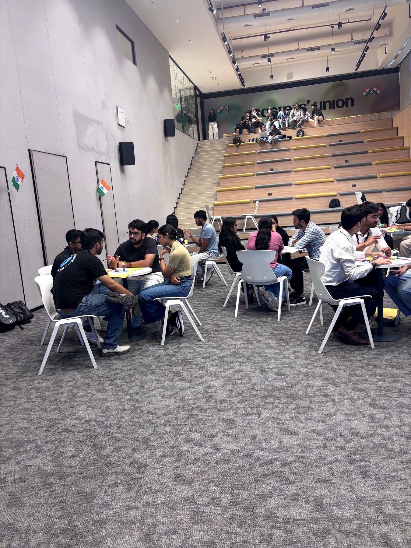Wide view of the auditorium with teams working at round tables